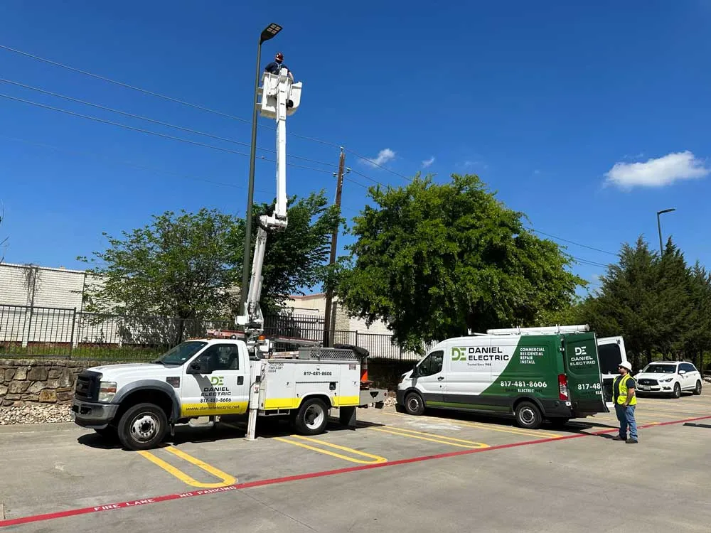 Two Daniel Electric bucket trucks and a green van at a parking lot
